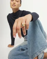 Anillo de aleación de metales bañado en oro 18k, con diseño de banda ancha y una forma de bola en la parte superior.