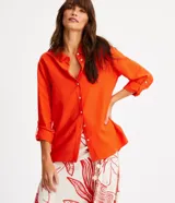 Camisa de manga larga color verde lima, con cuello camisero y botonadura frontal. Presenta un dobladillo trasero más largo que el delantero.