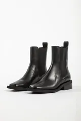 Bota tipo Chelsea de cuero color beige, con paneles laterales elásticos en color negro, puntera cuadrada y suela de goma negra con tacón bajo.