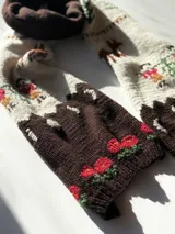 Bufanda extra large tejida a mano en 100% lana merino, con diseño jacquard inspirado en la tradición textil que presenta escenas campestres con ciervos, pequeños personajes y detalles florales.