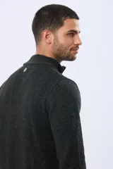 Buzo tejido de punto grueso en color azul marino, con cuello alto y cierre frontal parcial. Presenta detalles en gamuza en la zona del cierre y una textura en relieve en toda la prenda.