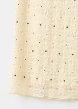 Falda midi de corte recto, confeccionada en tejido texturizado de color beige con pequeñas tachas metálicas distribuidas en el diseño y forro interior.
