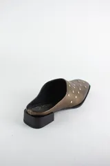 Zueco de cuero color bronce con punta almendrada y detalle de tachas metálicas doradas en toda la capellada. Posee un taco cuadrado bajo de 3 cm.