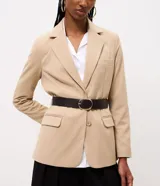 Blazer sastre color beige, de corte estructurado y calce al cuerpo, con solapa clásica, bolsillos con solapa en los laterales, bolsillo superior y cierre frontal de un botón.