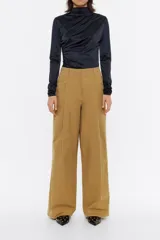 Pantalón de vestir color marrón claro, de corte ancho, con pinzas en la parte delantera, bolsillos laterales y trabillas en la cintura.