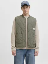 Chaleco acolchado color verde oliva, con diseño de matelassé, cuello estilo baseball y cierre frontal con botones a presión. Cuenta con dos bolsillos frontales y un bolsillo pequeño en el pecho con etiqueta de marca.