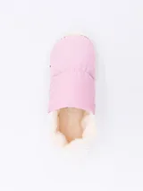 Pantuflas tipo slip-on, color rosado, con capellada acolchada y forro interior de pelo sintético color crema. Suela blanca de goma.