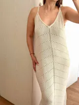 Vestido largo tejido en hilo de algodón y lurex color beige claro, con escote en V, tiras regulables en los hombros y tajos laterales. Presenta un patrón de puntos calados en forma de zigzag.