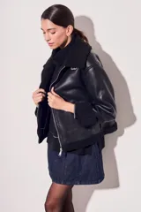 Campera negra de cuero sintético con cuello y puños de piel sintética. Corte oversize y cierre frontal con cremallera.