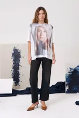 Remera de manga corta con cuello redondo y corte holgado, confeccionada en algodón. Presenta una estampa fotográfica frontal de una mujer con gorro de piel.