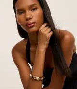 Pulsera dorada rígida con diseño de eslabones que simulan cañas de bambú.