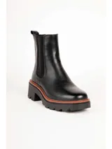 Bota tipo Chelsea de color negro, con elásticos laterales, suela track y taco cuadrado con detalle en tono marrón.