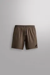 Pantalón corto deportivo color marrón oliva, confeccionado en tejido técnico ligero y elástico, con forro interior. Presenta cintura elástica ajustable con cordón, bolsillos frontales, bolsillo de seguridad trasero con cierre y aberturas laterales en el bajo.