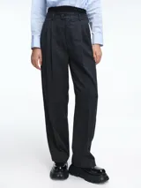 Pantalón sastrero de corte recto y tiro alto, confeccionado en tela gris con sutil estampado a cuadros. Presenta una pretina elástica de tejido negro en la parte superior, cierre frontal con botón y pinzas que definen su silueta estructurada.