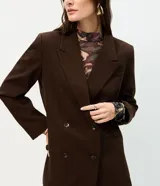 Blazer oversized estructurado marrón de corte cruzado con solapa amplia, bolsillos integrados y cuatro botones frontales.