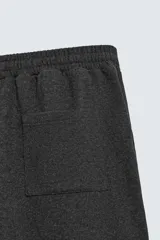 Pantalón de corte wide fit en tejido con acabado cepillado, color gris oscuro. Presenta cintura elástica con cordón ajustable, bolsillos delanteros y bolsillos traseros de plastrón.