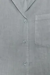 Camisa de lino con cuello solapa, manga larga con puños y cierre frontal con botones. Presenta un bolsillo de plastrón en el delantero.