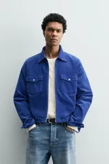 Sobrecamisa regular fit de Zara, confeccionada en pana de algodón color azul con efecto lavado. Cuenta con cuello solapa, manga larga con puño y botón a presión, bolsillos frontales de plastrón con solapa y cierre de cremallera.