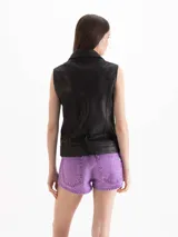 Chaleco de cuero ovino graneado negro, de silueta recta y calce relajado. Cuenta con cuello con solapas pronunciadas, cierre metálico diagonal y detalles en herrajes dorados.