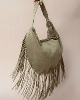 Cartera tipo hobo de gamuza color beige, con diseño amplio y detalle de flecos largos en todo el contorno. Presenta un asa con pespuntes artesanales y cierre superior.