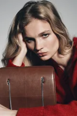 Bolso de hombro de piel marrón oscuro, formato rígido y rectangular, con detalle de pespuntes que crean un patrón de cuadrados. Posee triple compartimento y doble asa de hombro en cadena metálica dorada.