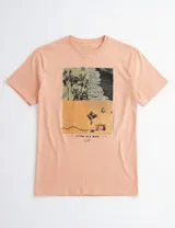 Remera de manga corta color naranja, con estampa fotográfica frontal de estilo playero y texto decorativo.