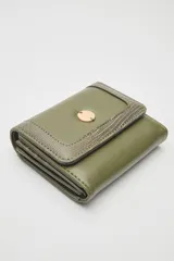 Billetera compacta de cuero sintético negro, con solapa que combina texturas lisas y efecto reptil. Incluye un aplique metálico circular con logo grabado en el frente y cierre con broche.