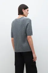 Cardigan gris melange de tejido de punto con diseño texturizado, manga corta y cierre frontal con botones.