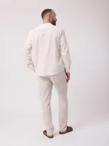 Camisa de lino color crudo, de manga larga con puños abotonados y cuello mao.