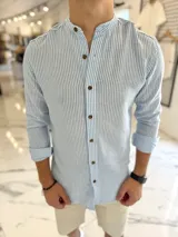 Camisa de lino a rayas celestes y blancas, con cuello mao y botones frontales en tono marrón.