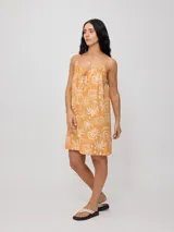 Vestido corto color naranja con estampado de motivos playeros en blanco, de breteles finos y corte suelto.