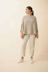 Poncho de tejido de punto con cuello alto y aberturas laterales para los brazos, de diseño holgado y minimalista.