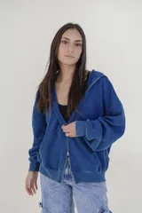 Campera con capucha de tejido polar o felpa, color azul oscuro con efecto desgastado o lavado. Diseño tipo canguro con cierre frontal.