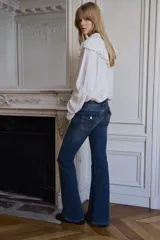 Jean de tiro bajo con corte acampanado desde la rodilla. Confeccionado en denim con leve stretch, presenta bolsillos delanteros abiertos y bolsillos traseros con solapa y botón.