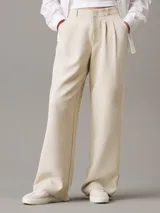 Pantalón de vestir color beige, de corte recto y tiro alto, confeccionado en crepé elástico. Presenta cintura plisada, bragueta con cremallera y cierre oculto, bolsillos laterales y traseros de ojal.