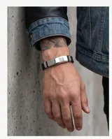 Pulsera de diseño moderno compuesta por una banda de goma negra y una placa central de acero inoxidable pulido.