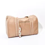 Bolso tipo duffel color beige con textura símil cuero, doble asa corta y correa larga desmontable. Cierre superior con cremallera y bolsillo frontal con cierre. Incluye llavero decorativo con diseño geométrico.