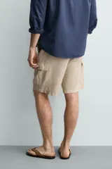 Bermuda cargo regular fit color beige, confeccionada en mezcla de algodón y lino con efecto lavado. Cuenta con bolsillos laterales tipo cargo con solapa en las perneras, bolsillos frontales, cierre frontal con cremallera y botón, y presillas para cinturón.