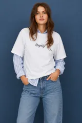 Remera blanca de corte holgado con estampa frontal en tipografía cursiva que dice Uruguay y cuatro estrellas pequeñas.