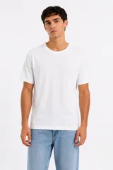 Remera blanca de manga corta en algodón, de corte holgado y cuello redondo, con pequeño texto estampado en el centro del pecho.