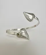 Pulsera rígida abierta de plata 950 con forma de corazón en los extremos y detalle de piedra engarzada.