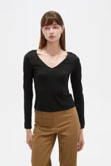 Remera negra de manga larga y calce al cuerpo, confeccionada en poliéster con diseño calado y escote en V.