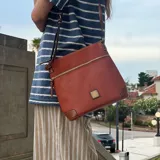 Bandolera color marrón con textura símil cuero, cierre superior con cremallera y bolsillo frontal con cierre.