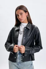 Sobrecamisa de cuero sintético en color negro, con cuello camisero, cierre frontal con botones metálicos a presión y mangas largas con puños abotonados.