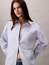 Camisa de popelina de algodón de corte relaxed, color celeste, con cuello clásico, cierre frontal con botones y bolsillo en el pecho con monograma CK bordado.