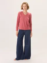 Remera blanca de manga larga con escote en V y detalles de alforzas verticales en el frente y mangas.