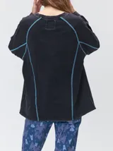 Remera de manga larga MUTMA Sticha, color negro con efecto acid wash y costuras decorativas expuestas en color celeste brillante. Cuenta con corte clásico, cuello redondo a la base y calce holgado.