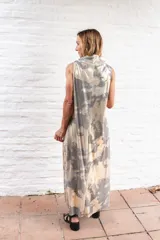 Vestido largo de corte recto y holgado, con cuello tipo polera drapeado y sin mangas. Presenta un estampado abstracto en tonos grisáceos y beige.