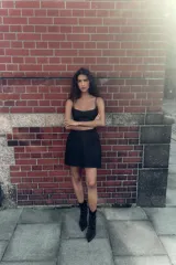 Vestido corto de corte ajustado con escote tipo bustier y tirantes finos. Presenta costuras verticales que definen la silueta y cierre posterior con cremallera oculta.