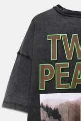 Camiseta de cuello redondo y manga corta con efecto lavado. Presenta una estampa frontal inspirada en la serie Twin Peaks con diseño de cortinas rojas y suelo geométrico.